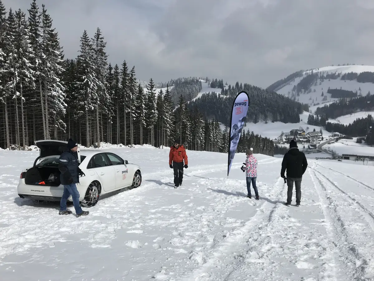Pewag Servo Schneetest — gebrandetes Testfahrzeug und Team auf der Piste