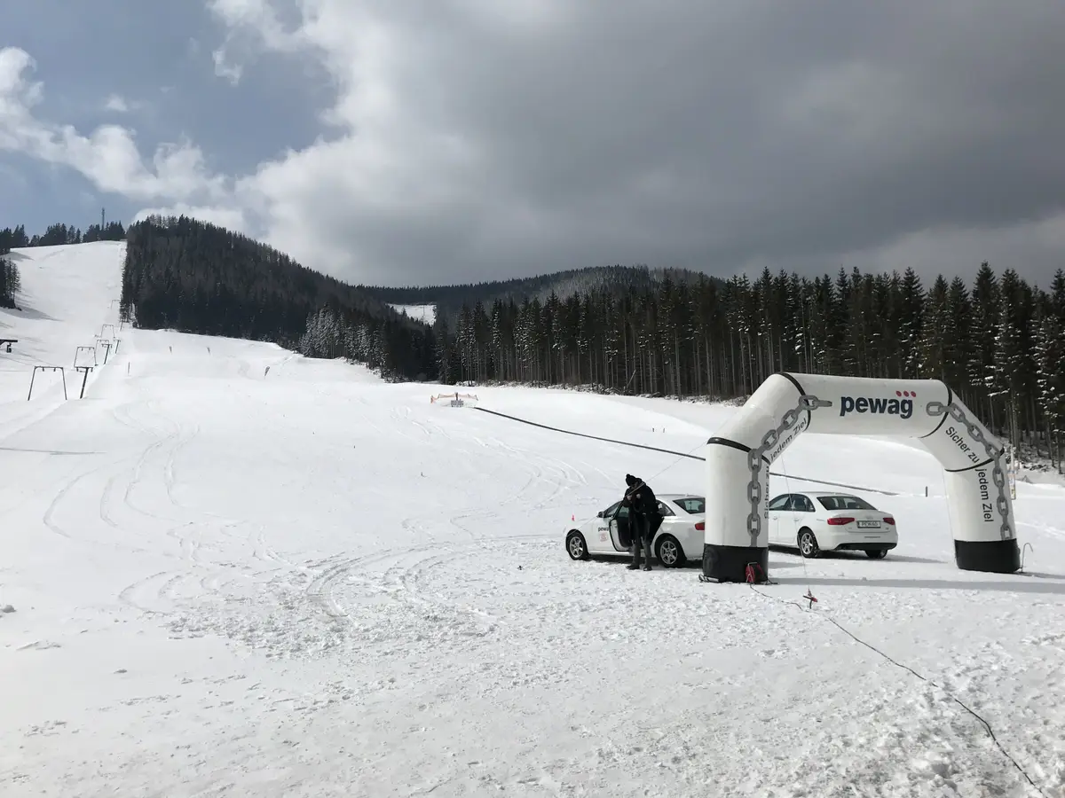 Pewag Servo Schneetest — Pewag-Branding am Pistenende mit Testfahrzeugen